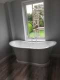 A bath tub in front of an open window with scaffolding on the other side.