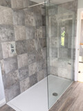 A completed shower unit with alternating light and dark grey tiles in the background.