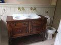 A decorative basin and cabinet with an installed toilet on it's right
