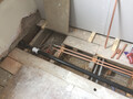 Showing under the floorboards of a bathroom, and the piping which was installed under them.