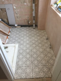 A bathroom floor with tiles installed and arranged in a repeating, geometric pattern.