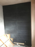 A bathroom wall complete with black tiles installed.