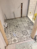 A bathroom floor with a number of tiles installed.
